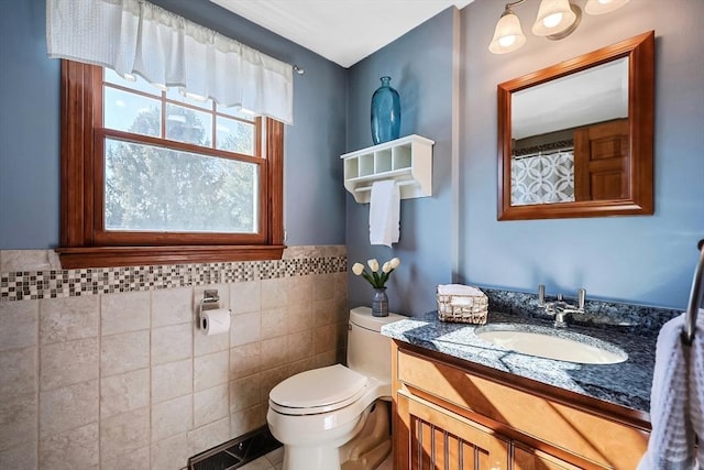 bathroom featuring toilet, vanity, tile walls, wainscoting, and tile patterned floors