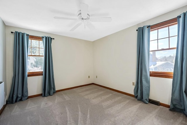 spare room with light colored carpet, ceiling fan, visible vents, and baseboards