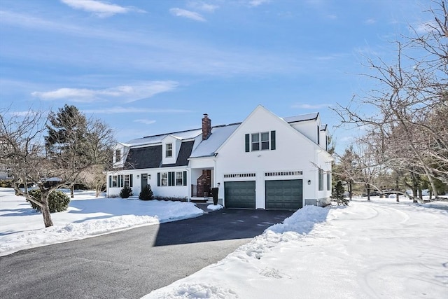 view of front of home featuring a garage, driveway, and a chimney