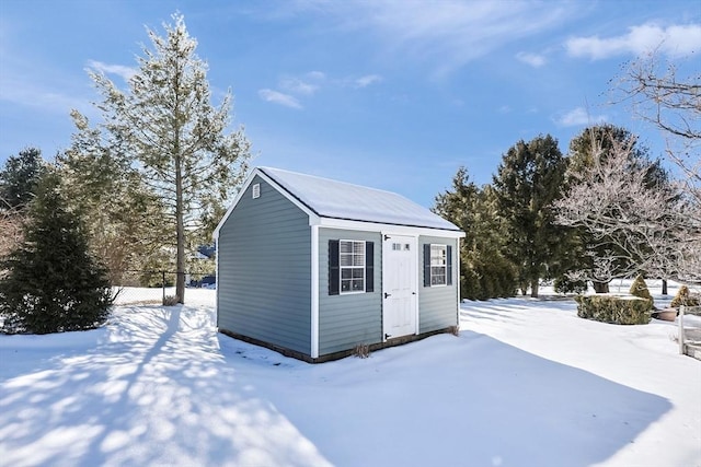 snow covered structure featuring an outdoor structure and fence