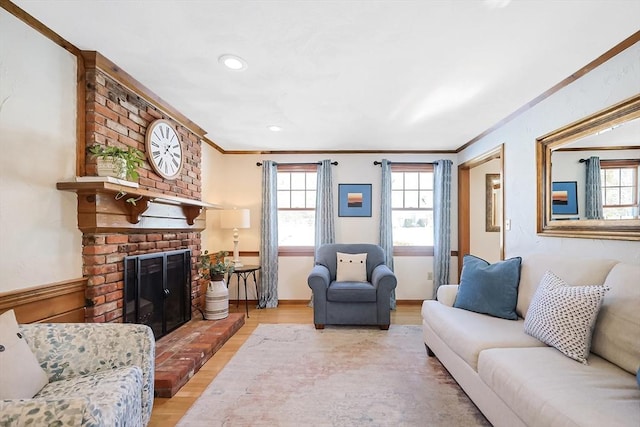 living room with a brick fireplace, baseboards, ornamental molding, and wood finished floors