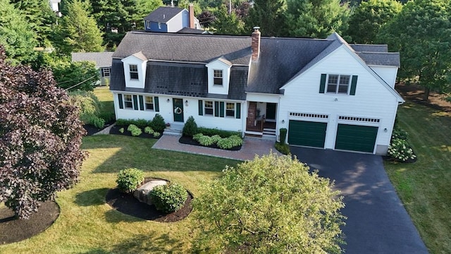 view of front of house featuring driveway, a garage, a chimney, and a front lawn