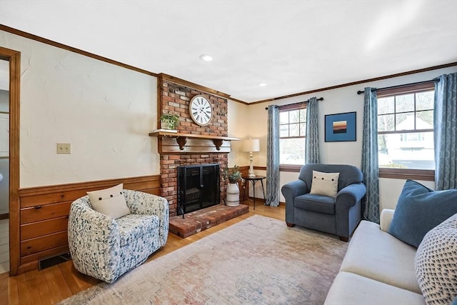 living area with a brick fireplace, visible vents, crown molding, and wood finished floors