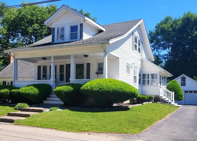 view of front of house with covered porch, a garage, an outdoor structure, and a front yard