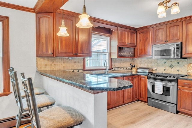 5 Upland St, Auburn, MA 01501 - kitchen featuring appliances with stainless steel finishes, a kitchen breakfast bar, light wood-type flooring, dark stone countertops, and a peninsula