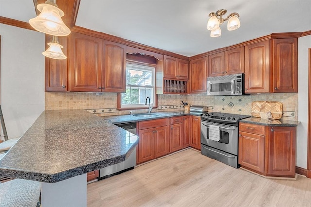5 Upland St, Auburn, MA 01501 - kitchen featuring stainless steel appliances, a peninsula, light wood-style flooring, brown cabinetry, and backsplash