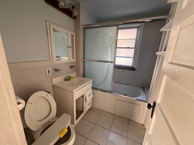 full bathroom featuring tile patterned floors, vanity, toilet, and bath / shower combo with glass door