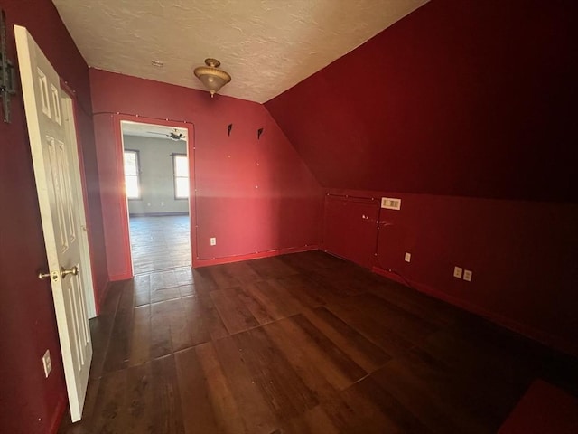 bonus room with ceiling fan, dark hardwood / wood-style flooring, lofted ceiling, and a textured ceiling