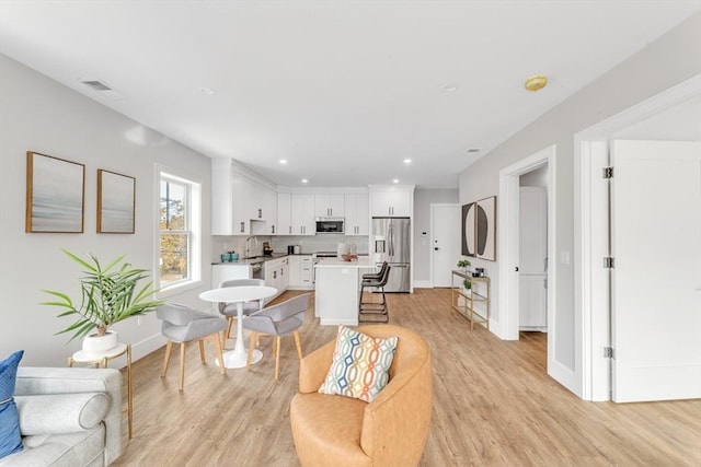 living area featuring visible vents, light wood-style flooring, baseboards, and recessed lighting