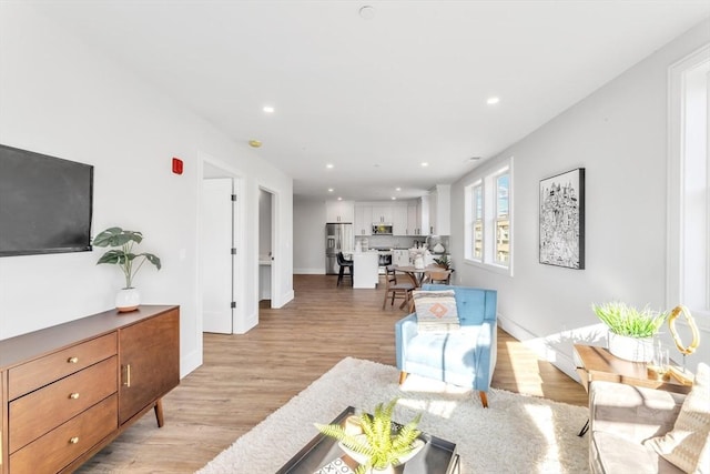 living room featuring light wood finished floors, baseboards, and recessed lighting