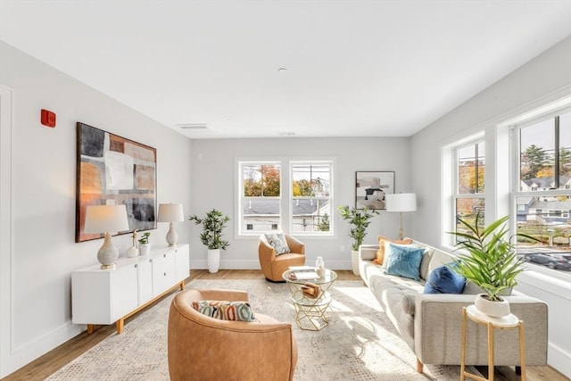 sitting room with baseboards, light wood-type flooring, and plenty of natural light