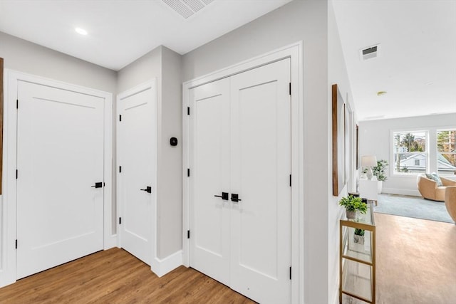 foyer entrance featuring baseboards, visible vents, and wood finished floors