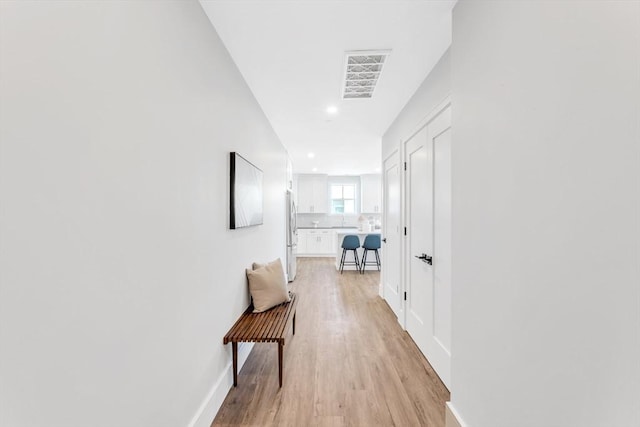 hall with baseboards, light wood-type flooring, visible vents, and recessed lighting