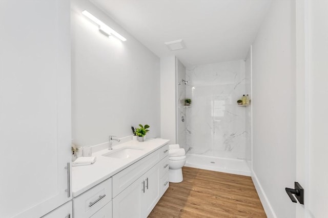 bathroom with toilet, a marble finish shower, wood finished floors, and vanity