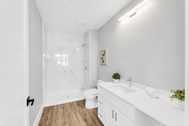full bathroom featuring toilet, a marble finish shower, wood finished floors, and vanity