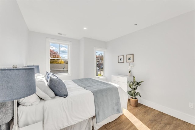 bedroom with baseboards, visible vents, recessed lighting, and wood finished floors
