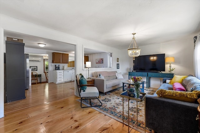 living room with light hardwood / wood-style flooring, a wall mounted air conditioner, and a chandelier