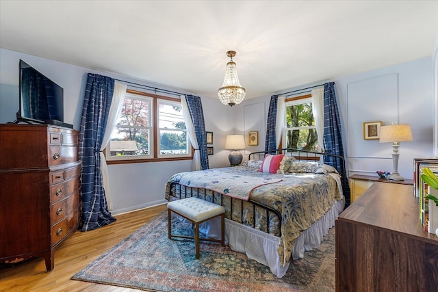 bedroom with light wood-type flooring, a chandelier, and multiple windows