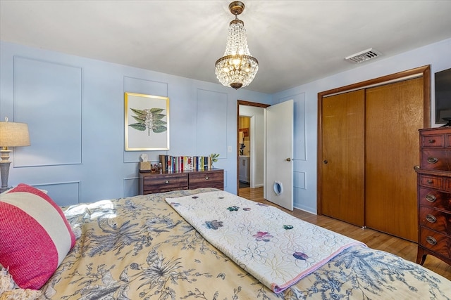 bedroom featuring light hardwood / wood-style floors, an inviting chandelier, and a closet