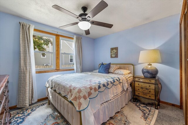 bedroom featuring ceiling fan, light colored carpet, and a textured ceiling