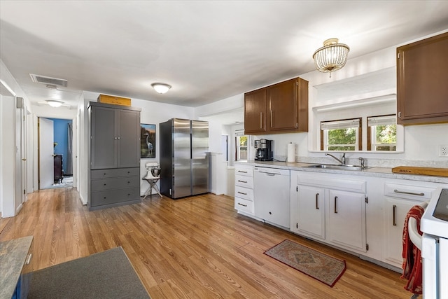 kitchen featuring light wood-type flooring, white appliances, white cabinetry, and sink