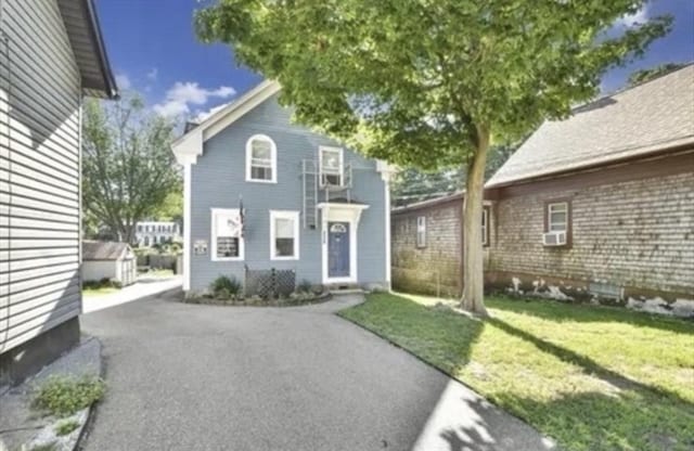 view of front facade featuring driveway, a front yard, and cooling unit