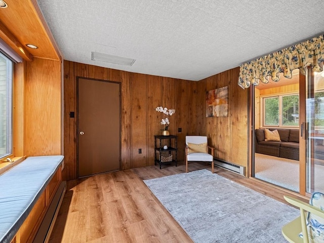 living area featuring baseboard heating, wooden walls, and a textured ceiling