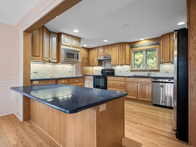 kitchen with appliances with stainless steel finishes, decorative backsplash, light hardwood / wood-style flooring, and sink