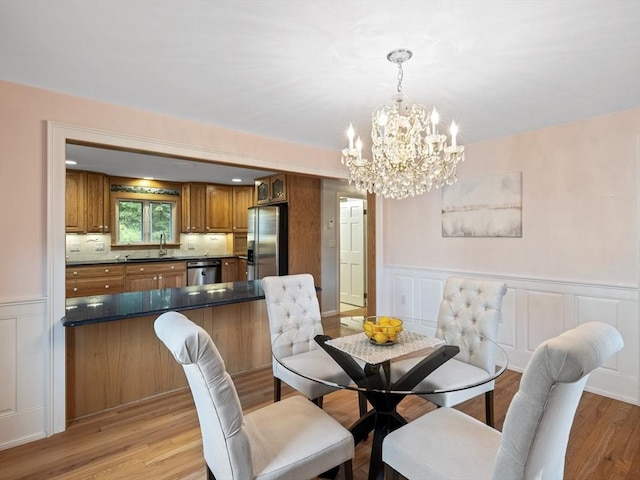 dining space with a notable chandelier, light hardwood / wood-style floors, and sink