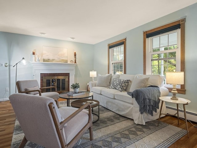 living room featuring a brick fireplace, baseboard heating, and dark hardwood / wood-style floors