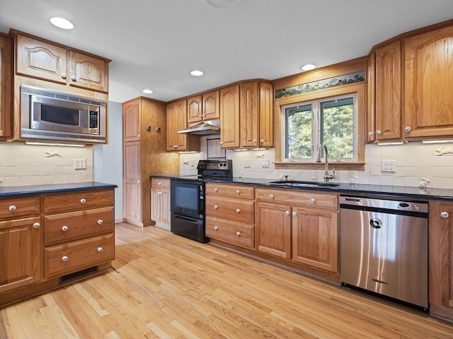 kitchen with tasteful backsplash, light wood-type flooring, sink, and stainless steel appliances