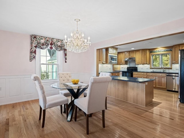 dining space featuring an inviting chandelier, light hardwood / wood-style floors, and sink