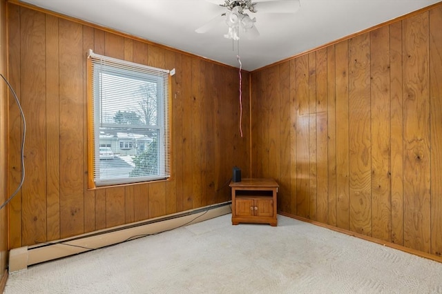 carpeted spare room with a baseboard radiator, wooden walls, and ceiling fan