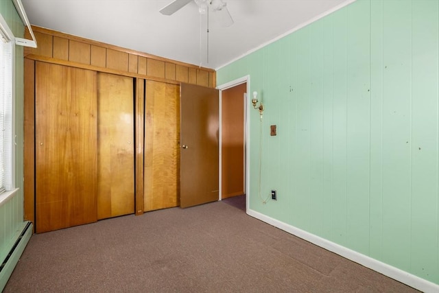 unfurnished bedroom with ceiling fan, carpet, baseboard heating, and a closet