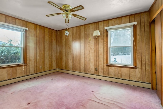 carpeted empty room with ceiling fan and wood walls