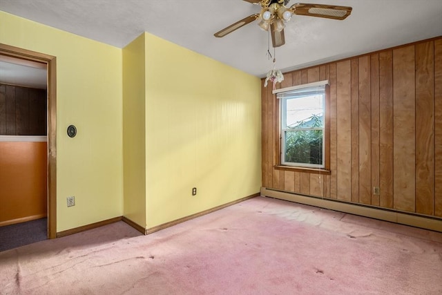 spare room with ceiling fan, light colored carpet, baseboard heating, and wood walls