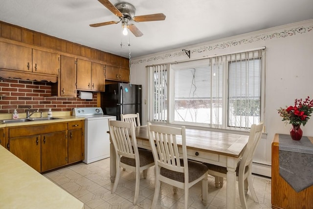 kitchen with black refrigerator, washer / clothes dryer, sink, ceiling fan, and baseboard heating