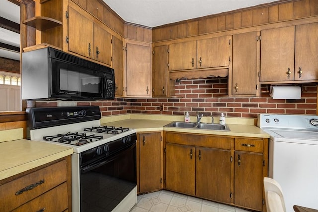 kitchen with light tile patterned flooring, tasteful backsplash, washer / dryer, sink, and gas range oven