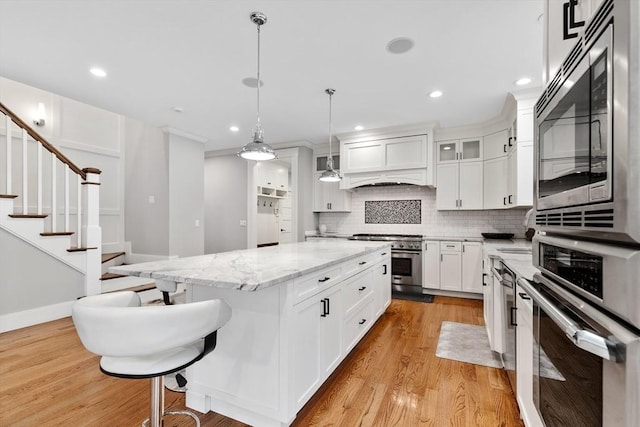 1 Apollo Cir, Lexington, MA 02421 - kitchen featuring stainless steel appliances, decorative backsplash, a kitchen island, white cabinetry, and light wood-style floors