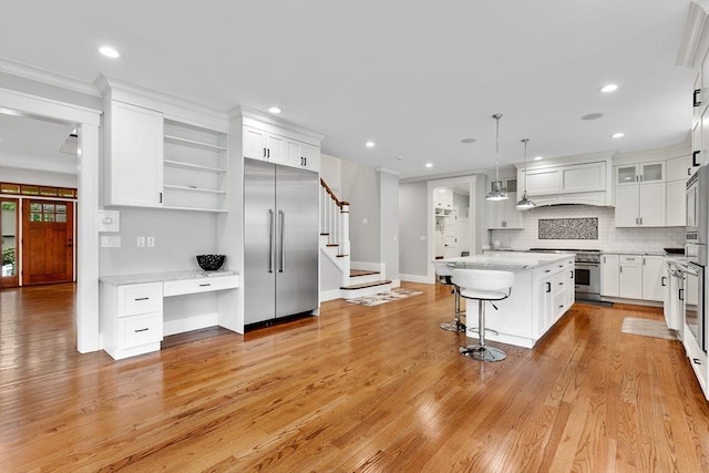 1 Apollo Cir, Lexington, MA 02421 - kitchen with high quality appliances, a center island, white cabinets, decorative backsplash, and light wood finished floors