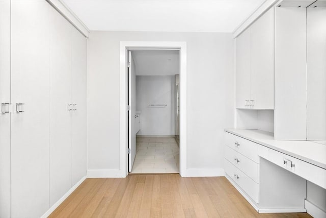 spacious closet with built in desk and light hardwood / wood-style floors