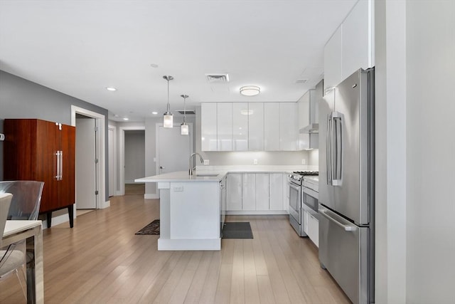 kitchen with decorative light fixtures, white cabinetry, sink, stainless steel appliances, and light wood-type flooring