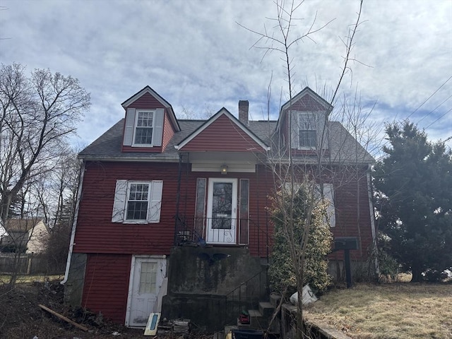 view of front facade with roof with shingles and a chimney