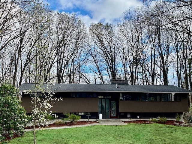 view of front facade with a chimney and a front lawn