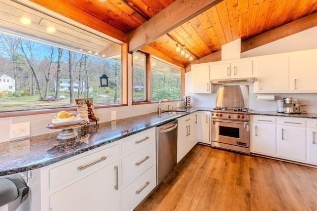 kitchen with wood ceiling, a sink, lofted ceiling with beams, stainless steel appliances, and wood finished floors