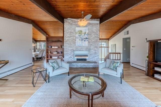 living area with vaulted ceiling with beams, wood ceiling, a baseboard radiator, ceiling fan, and visible vents