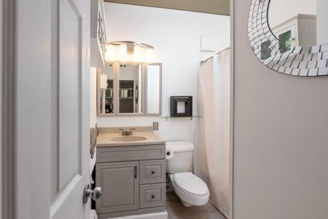 full bath featuring toilet, a shower with curtain, and vanity