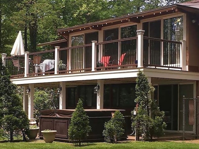 rear view of house with a balcony and a hot tub