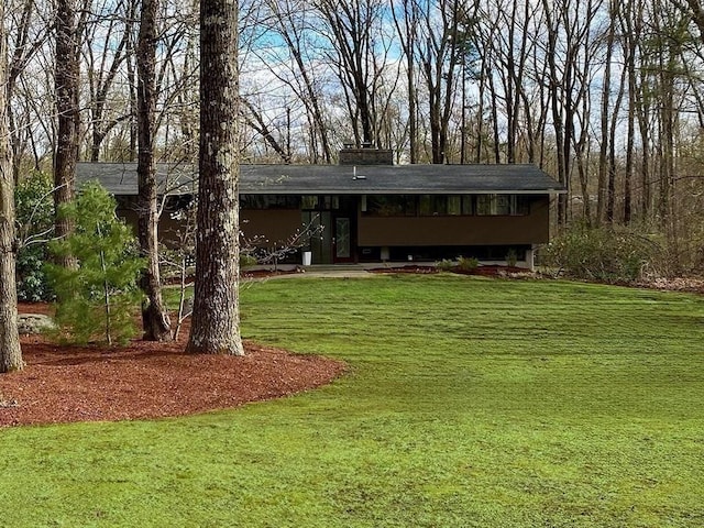 view of front of home with a chimney and a front yard