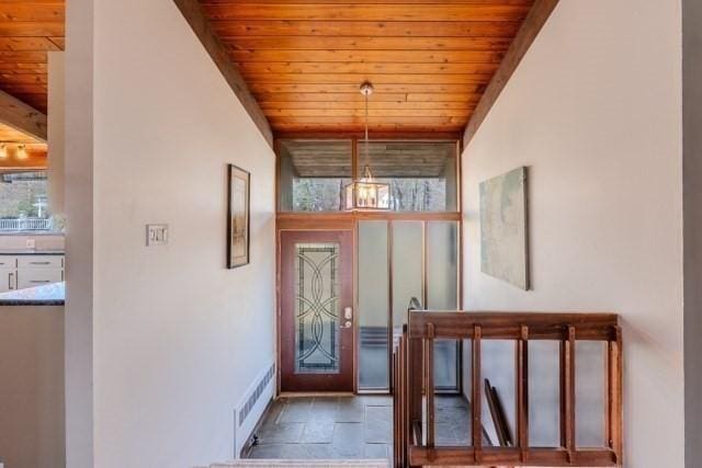 doorway with wooden ceiling, stone finish floor, and visible vents